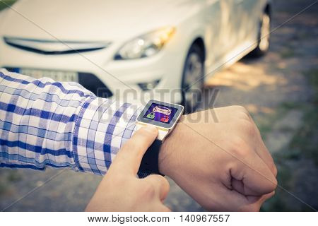 Close up shoot of male hands locking the car doors by using smart watch remote control security app.