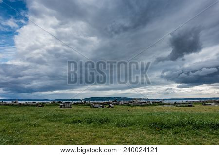 Dark Storm Clouds Hover Over A Green Meadow In Normany Park, Washington.