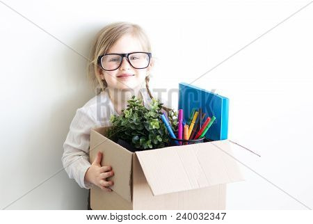Smart Little Girl Wearing Business Clothes And Glasses, Holding The Box With Documents And Her Stuff