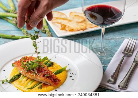 Seasoned Roasted Green Asparagus With Grilled Salmon On Polenta. Gourmet. The Hand Of A Cook Decorat