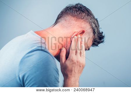 Male Having Ear Pain Touching His Painful Head Isolated On Gray Background