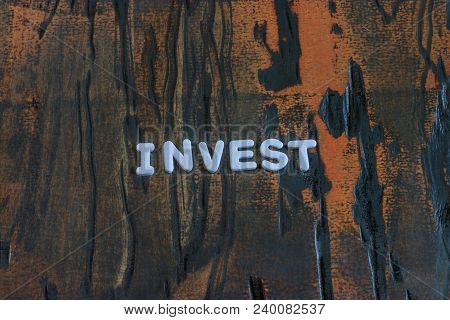 Invest Written In White Lettering On Weathered Dark Wood