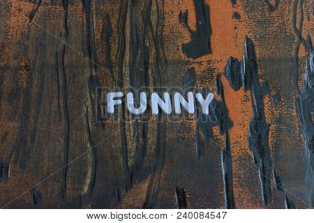 The Word Funny Written In White Block Letters On A Orange And Brown Wood Surface