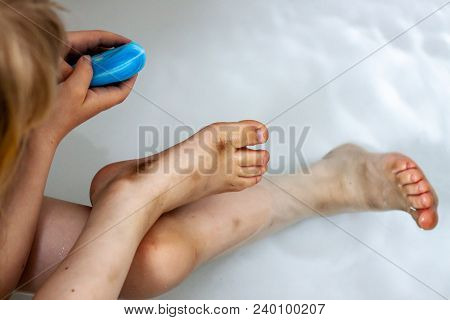 Little Girl Cleaning Her Dirty Feet In The Bathtub