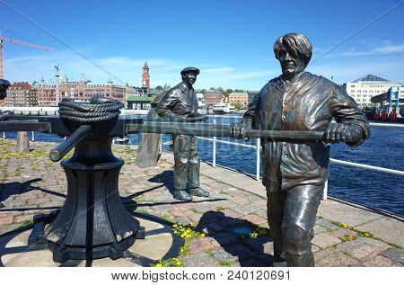 Helsingborg, Sweden - 04 May, 2018: Detail of Maritime sculpture of sailors working a capstan with Helsingborg old town on background