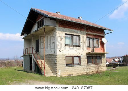 Family House Damaged By Shrapnels During War With Falling Facade, Visible Building Blocks, New Windo