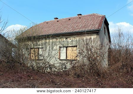 Small Suburban Family House Damaged By Shrapnels During War With Dilapidated Facade, Visible Bricks 