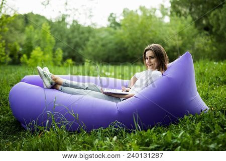 Pretty Young Woman Lying On Inflatable Sofa Lamzac Browse In Internet On Laptop While Resting On Gra