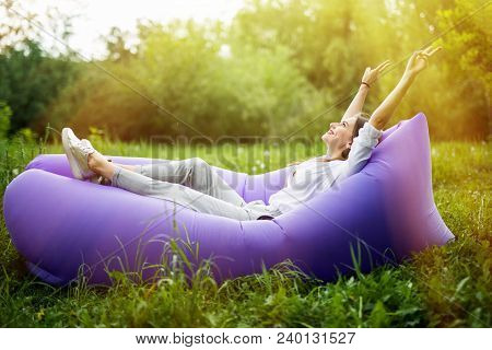I Am Free. Pretty Young Woman Lying On Inflatable Sofa Lamzac With Reised Hands In The Air While Res
