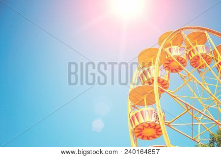 Bright Ferris Wheel Against The Blue Sky With A Sunlight Glare. Space For Text