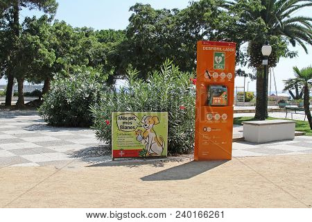 Blanes, Spain - September 11, 2014: Street Defibrillator And Poster About Cleaning Feces For Dogs In