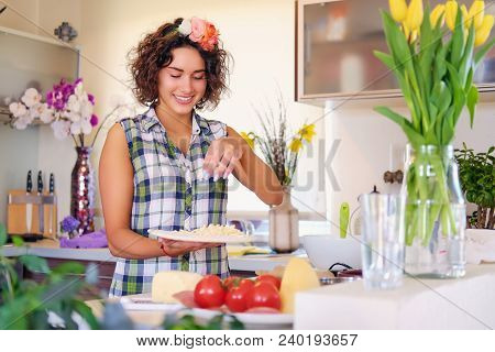 Positive Brunette Female With Curly Hair Makes Salad With Tomatoes And Potato In A Home Kitchen.