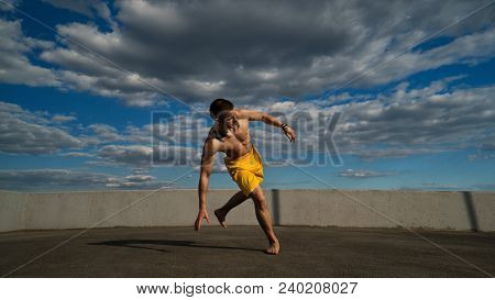 Tricking On Street. Martial Arts. Man Performs Leap With Support Of His Hand Barefoot. Shooted From 