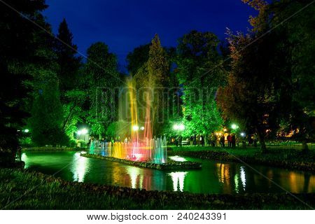 Beutiful Colourful Waterworks During Night In Polanica-zdrój In Poland Reflected In A Small Lake Wit
