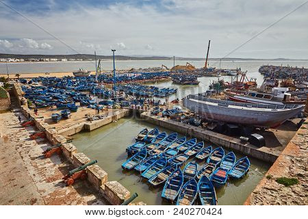 Essaouira Port In Morocco With Blue Fishing Boats And Ancient Famous Fort On Background On A Sunny D