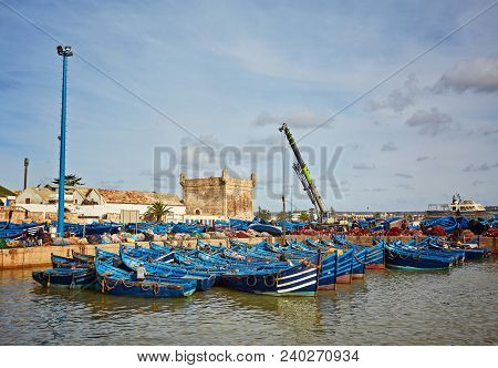 Essaouira Port In Morocco With Blue Fishing Boats And Ancient Famous Fort On Background On A Sunny D