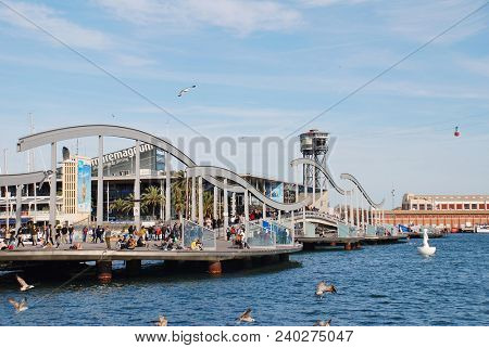 BARCELONA, SPAIN - APRIL 15, 2018: People cross the Rambla del Mar floating footbridge at Port Vell. Leading to the Moll d'Espanya, the bridge was completed in 1994.