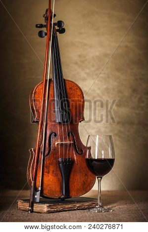 Front View Of A Classical Old Violin With Red Wine Glass
