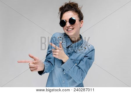 Young Girl In Round Glasses On A Gray Background. Portrait Of A Young Beautiful Girl. Charming Girl 