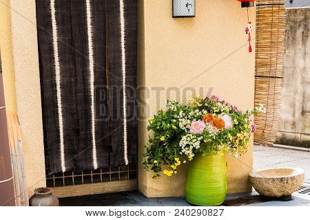 Green Vase With Wild Flowers On A City Street In Kyoto, Japan. Copy Space For Text.