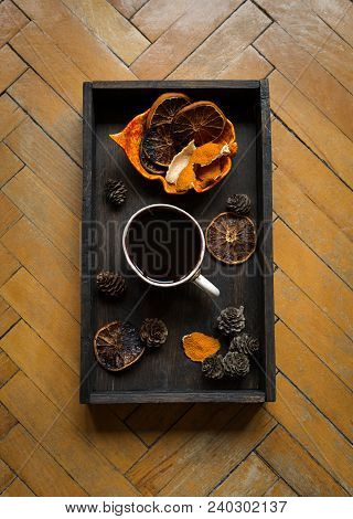 Some Dried Orange Peel, Cones And Dried Orange Slices With A Cup Of Hot Dlack Coffee On Black Wooden