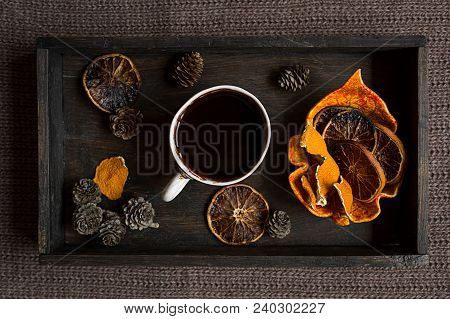 Some Dried Orange Peel, Cones And Dried Orange Slices With A Cup Of Hot Dlack Coffee On Black Wooden