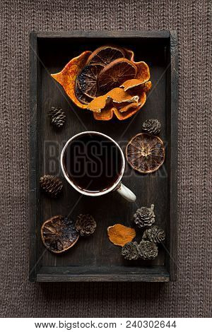 Some Dried Orange Peel, Cones And Dried Orange Slices With A Cup Of Hot Dlack Coffee On Black Wooden