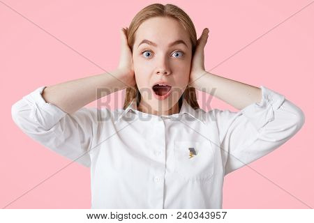 Photo Of Annoyed Female Plugs Ears As Hears Loud Music, Has Shocked Expression, Blue Eyes And Soft H