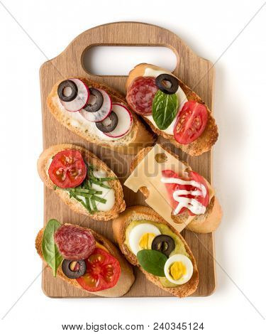 Open faced sandwich canape or crostini on a wooden serving board isolated on white background closeup. Top view.