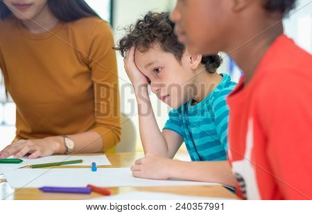 Caucasion Boy Kid With Sadness Emotion Sitting In Classroom In Kindergarten Preschool.bulying Depres