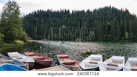Lacu Rosu Or Red Lake With Boats On The Shore. Landscape With A Picturesque Lake And A Pine Forest O