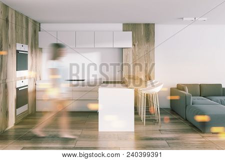 Woman In A Studio Apartment Kitchen And Living Room With A Wooden Bar And Built In Apliances. Concep