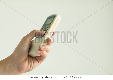 Hand Press Power Button On Remote Control Air Conditioner On White Background.