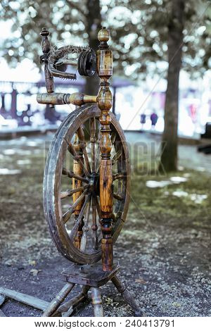 Old Spinning Wheel Stands In The Shade Of The Trees