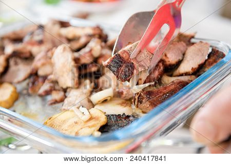 Table Background With Picnic Barbecue Meat On Table. Tongs With Piece Of Grilled Meat And Onion.