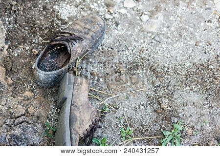 Pair Of Old Dirty Used Shoes.  Abandoned Discarded Boots Laying In Dust On Ground. Poverty Or Beggar