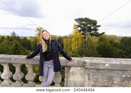 Pretty Girl Standing Near Concrete Railing With Green Trees Background. Concept Of Architectural Ele