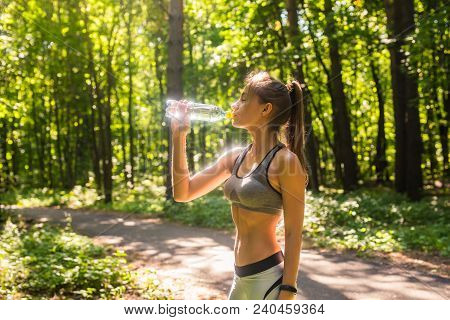 Young Woman Drinking Water After Running Outdoors.