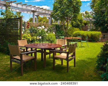 Landscaped Garden With Wooden Dining Table Set In The Shade Of Trees