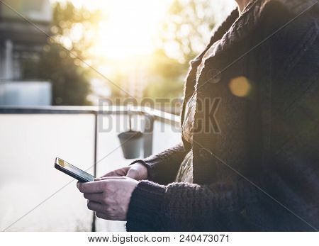 Closeup Of Woman Using Her Smart Phone Outside On Porch In Golden Evening Sunlight