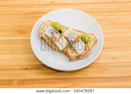 Open Sandwich Made Of Brown Sprouted Bread, Slices Of Fillet Of Pickled Atlantic Herring And Green O