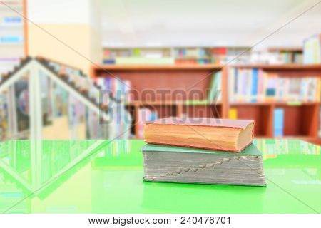 Old Book And Heap Treatise In School Library On Table Green. Blurry Bookshelves Background. Educatio