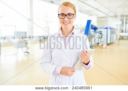 Waist-up Portrait Of Smiling Technologist Wearing White Coat Holding Digital Tablet In Hands And Pos