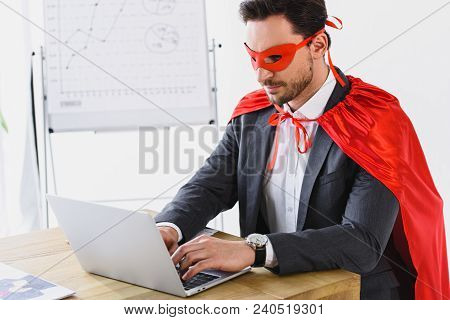 Super Businessman In Mask And Cape Working With Laptop In Office
