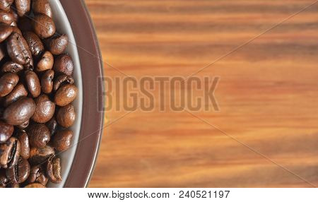 Edge Of A Saucer With Fried Coffee Beans On A Wooden Background. Texture, Wallpaper