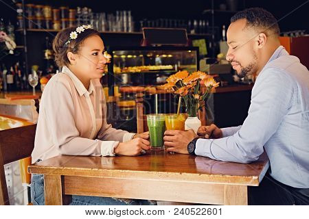 Black American Couple Talks And Drinks, Fresh Juice At A Cafe