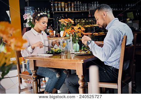 Black American Male And Female Eating Vegan Food In A Restaurant.