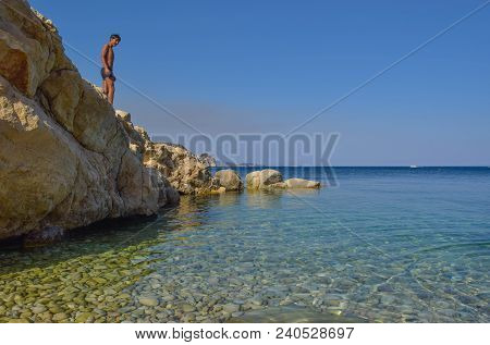 The Boy On The Rock In Sea. Marathias Beach, Zakynthos Island, Greece.