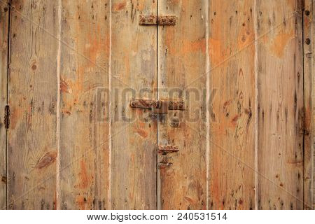 Wooden brown door background locked with rusty padlock. Timeworn, closed entrance provides safety and privacy. Close up view with details.