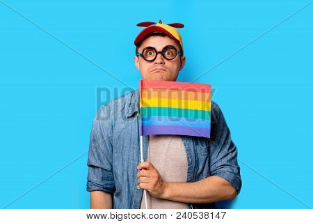 Young Nerd Man With Noob Hat Holding A Rainbow Flag On Blue Background